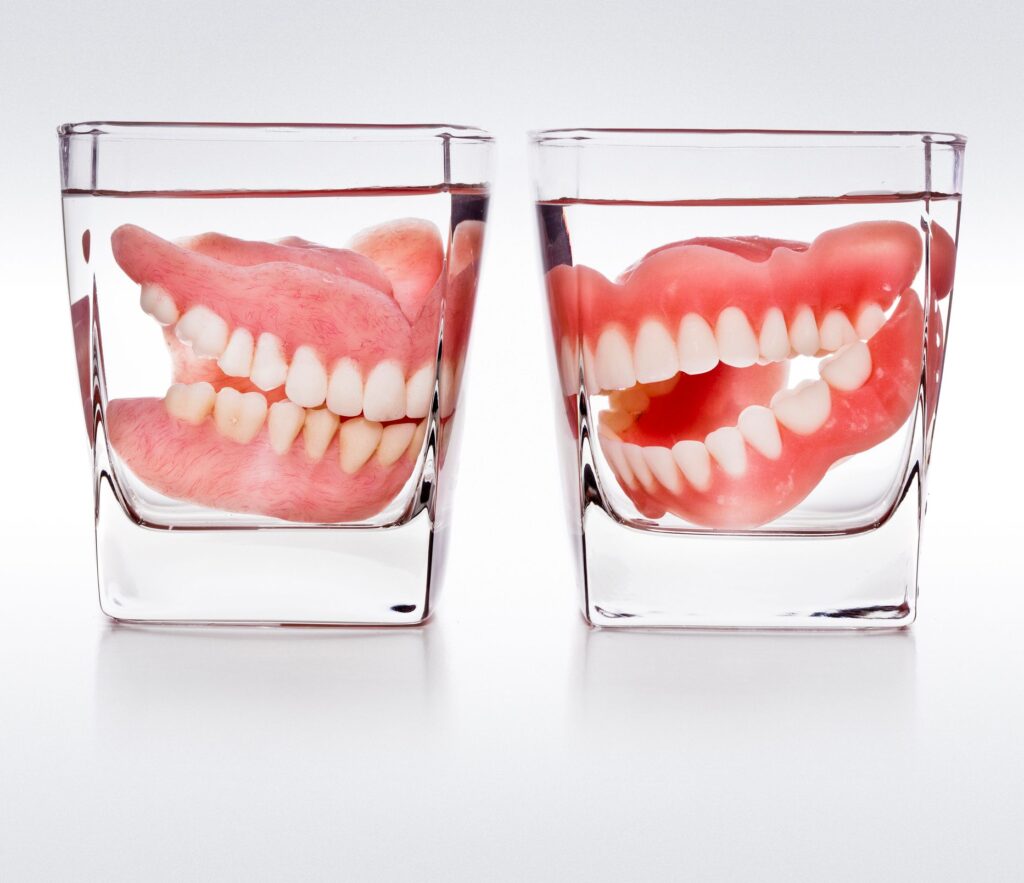 Dental bridges and implants in Santa Barbara, CA, with dentures in cups